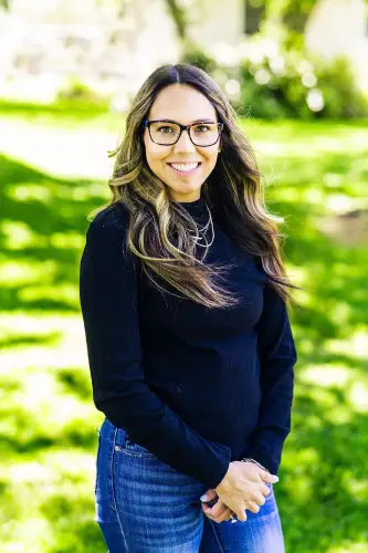 Smiling woman with glasses standing in park